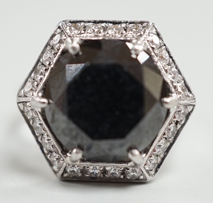 A modern 750 white metal and hexagonal cut black diamond set dress ring, with diamond chip set border, size N/O, gross weight 7.8 grams.